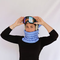 Model wearing a quilted puffer neck gaiter with ski goggles and helmet, front view