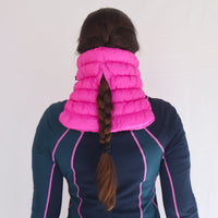 Quilted puffer neck gaiter in bright pink, shown from behind on model with braided hair