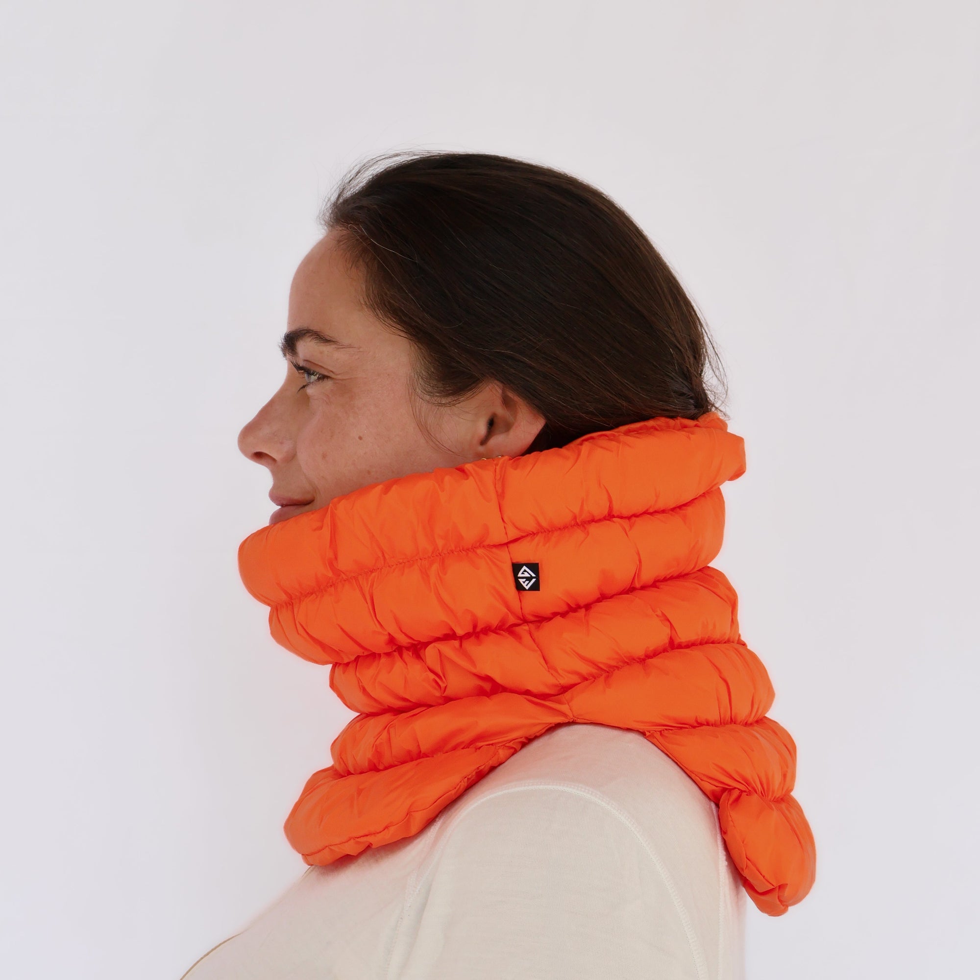 Puffy quilted neck gaiter in bright orange worn by a model, side profile view
