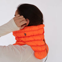 Quilted puffer neck gaiter in bright orange worn by model, side view