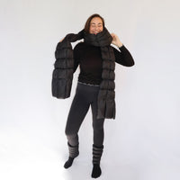 Model wearing a black quilted puffer scarf draped around neck and shoulders, smiling