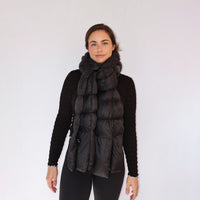 Black quilted puffer scarf worn draped around neck and shoulders, front view on model