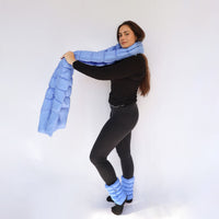 Model wearing a light blue quilted puffy scarf draped around neck, with matching puffy leg warmers
