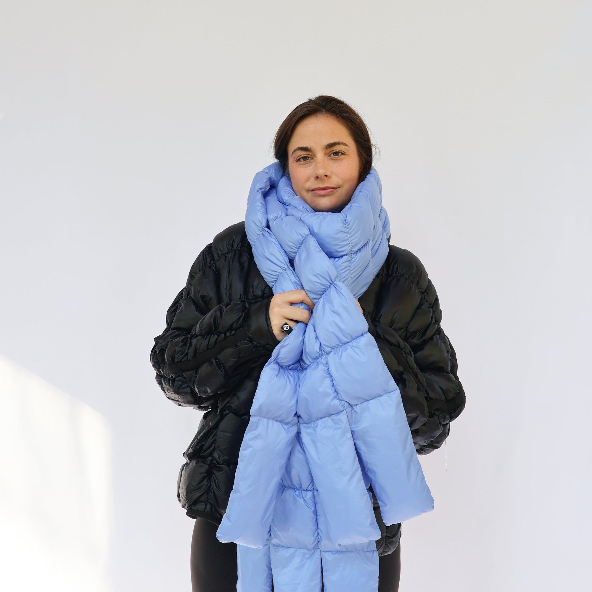 Light blue oversized puffy quilted scarf worn loosely around neck, front view on model