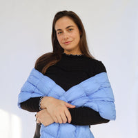 Light blue puffy scarf worn draped over shoulders on a model, front view
