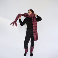 Model wearing an extra-long quilted puffer scarf in deep plum, styled around neck and trailing to floor