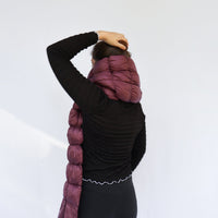 Puffy quilted scarf in deep plum worn around neck, back view on model