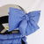 Large puffy bow in blue attached to a white ski helmet, side view
