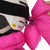 Bright pink ski helmet bow accessory being attached to a white ski helmet with goggles