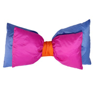 Oversized ski helmet bow accessory in pink, blue, and orange, bow-tie shape, studio shot