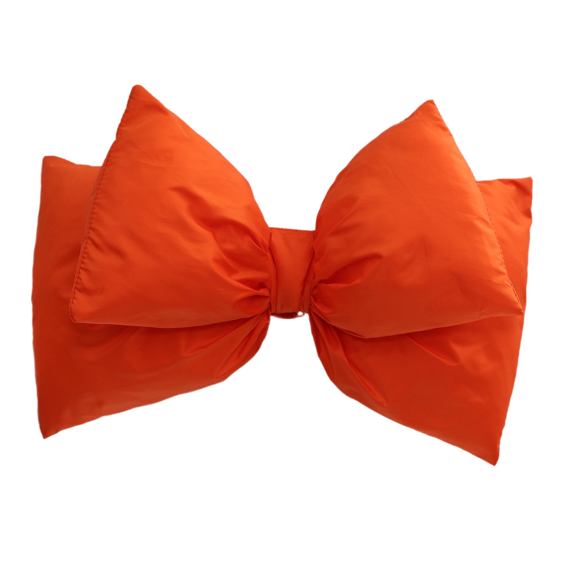 Large puffy oversized bow hair accessory in bright orange, flat lay view
