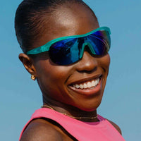 Wraparound athletic sunglasses with teal frame and blue mirrored lenses worn by smiling person