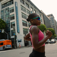 Athletic sunglasses with teal frame and blue mirrored lenses worn during outdoor run