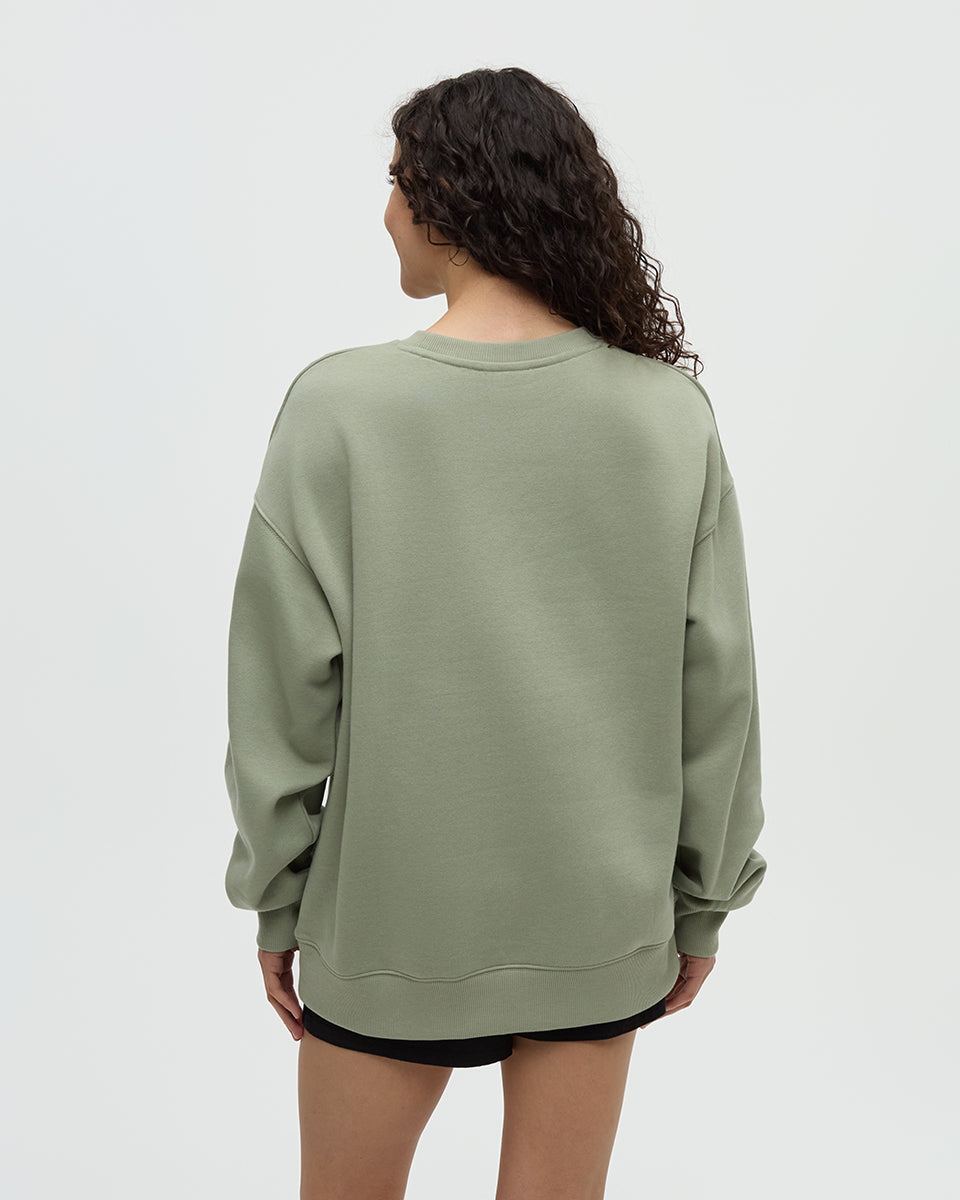 Light green crew neck sweatshirt shown from back view on model with curly hair