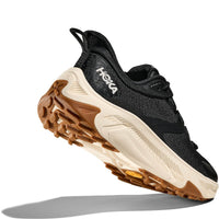 Black athletic running shoe with cream midsole and brown outsole, angled side view