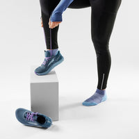 Person wearing blue ankle socks stepping on white cube, showing sock design and fit