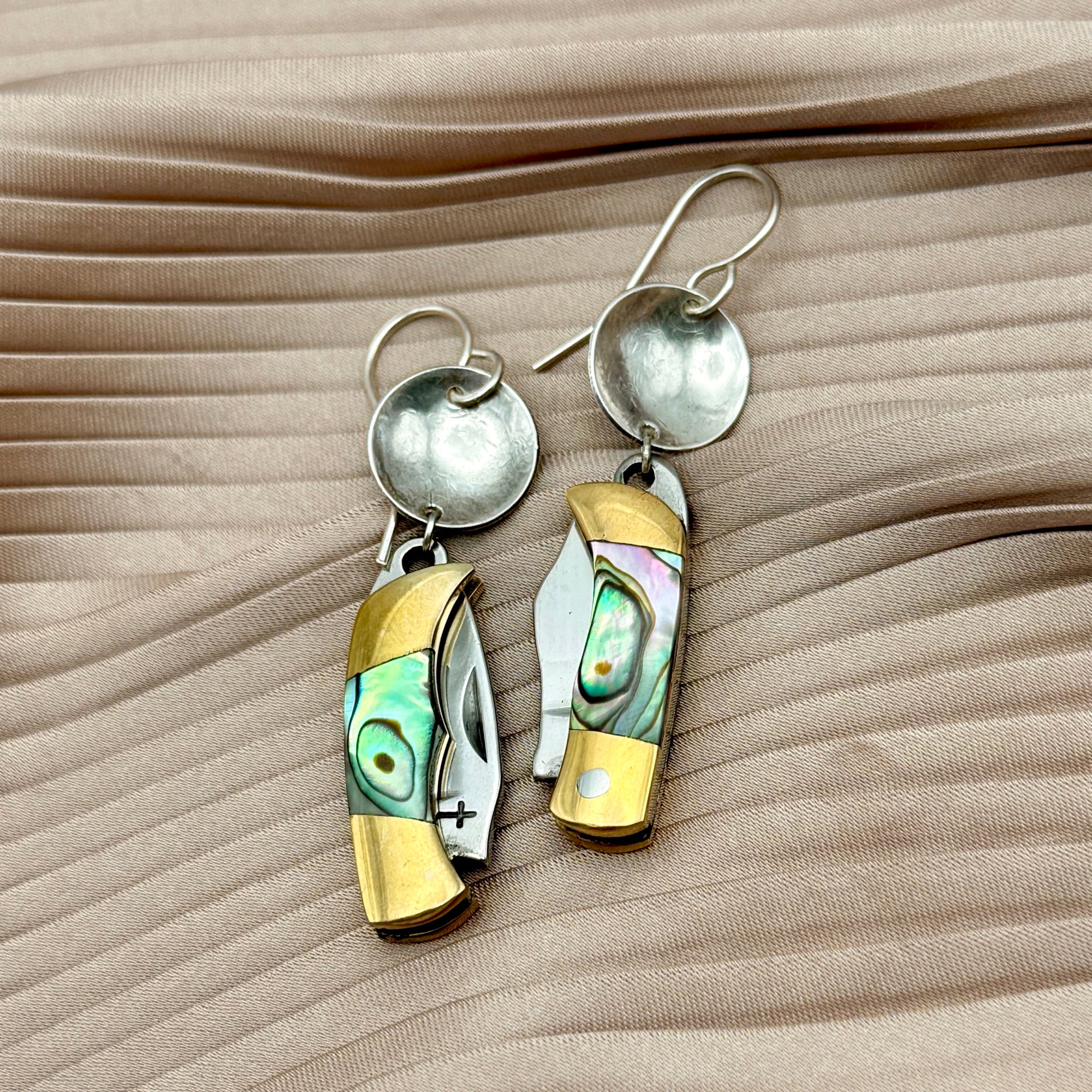 Dangle earrings featuring miniature pocket knives with abalone shell inlay and silver disc tops