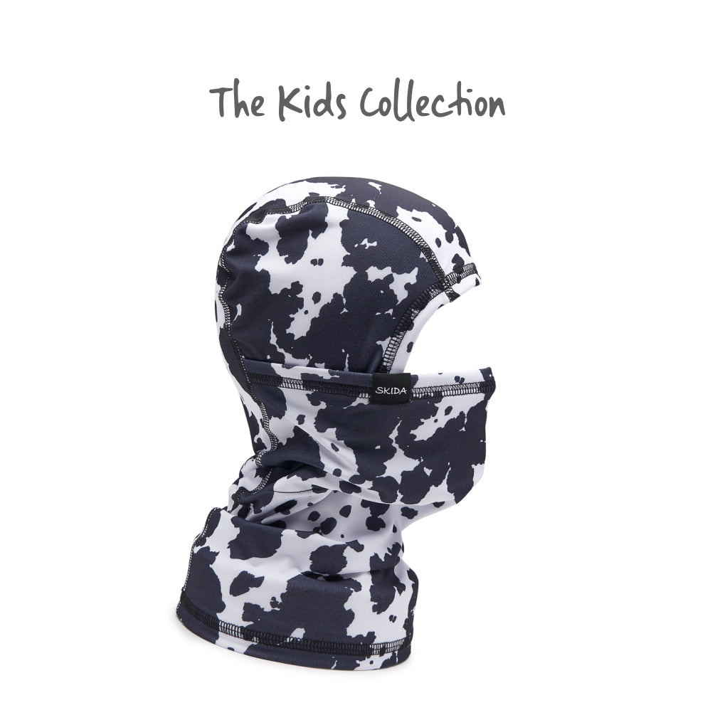 Kids balaclava with black and white cow print pattern, side view showing full hood and neck coverage