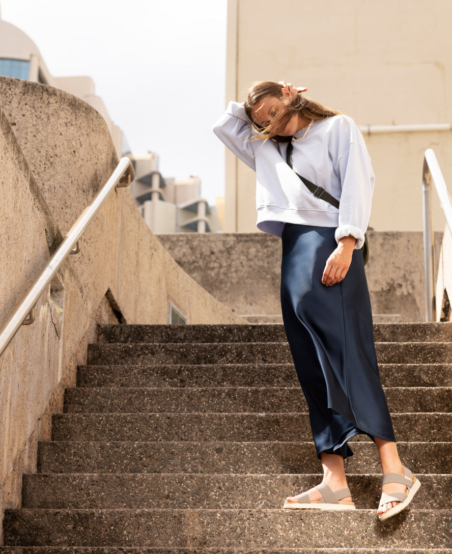 Light colored backstrap sandals worn by woman on concrete steps