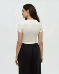 Woman wearing cream colored fitted short sleeve t-shirt, back view against white background