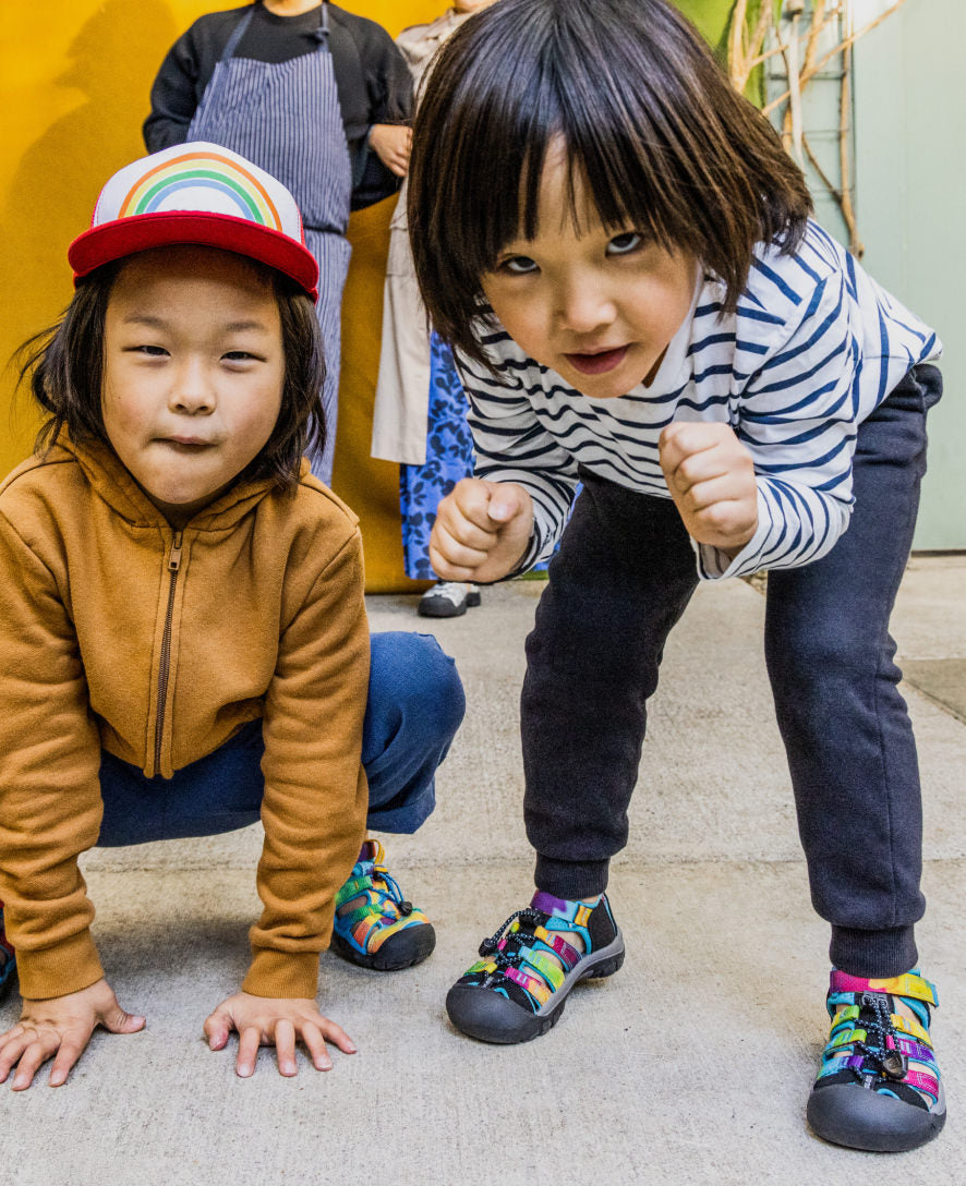 Two children wearing colorful striped athletic sandals in active play poses