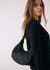 Black hobo bag worn on shoulder by model in dark green outfit