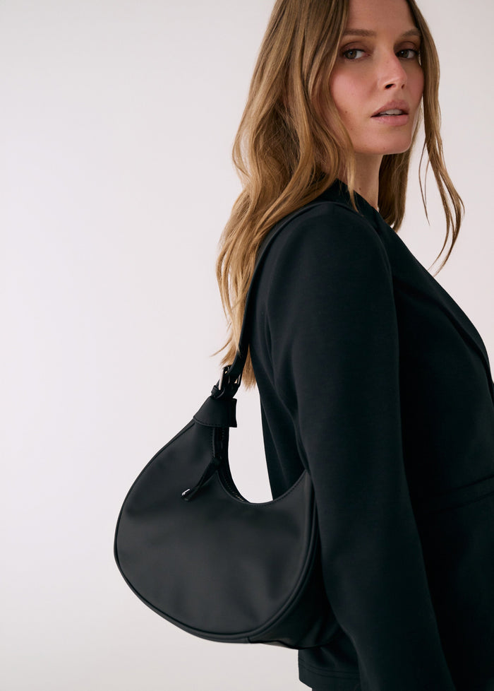Black hobo bag worn on shoulder by model in dark green outfit