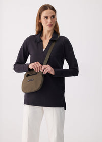 Olive green crossbody bag with top handle and logo strap, worn on model