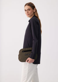 Olive green oval-shaped crossbody clutch bag held by model, side view