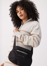 Black crossbody bag with top handle and adjustable strap, worn over shoulder on model