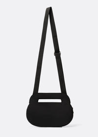 Black oval crossbody bag with adjustable logo strap and top carry handle, back view