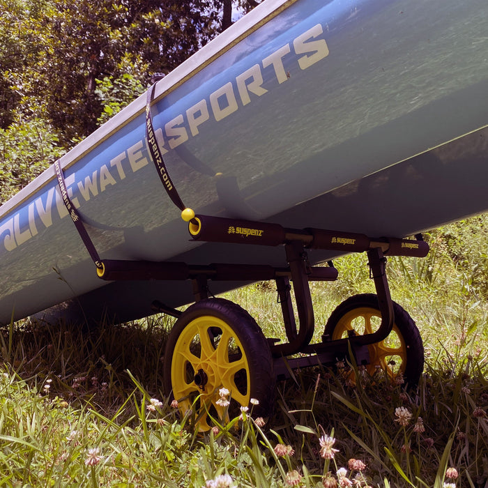 Gray kayak cart with yellow wheels holding watercraft in outdoor grass setting
