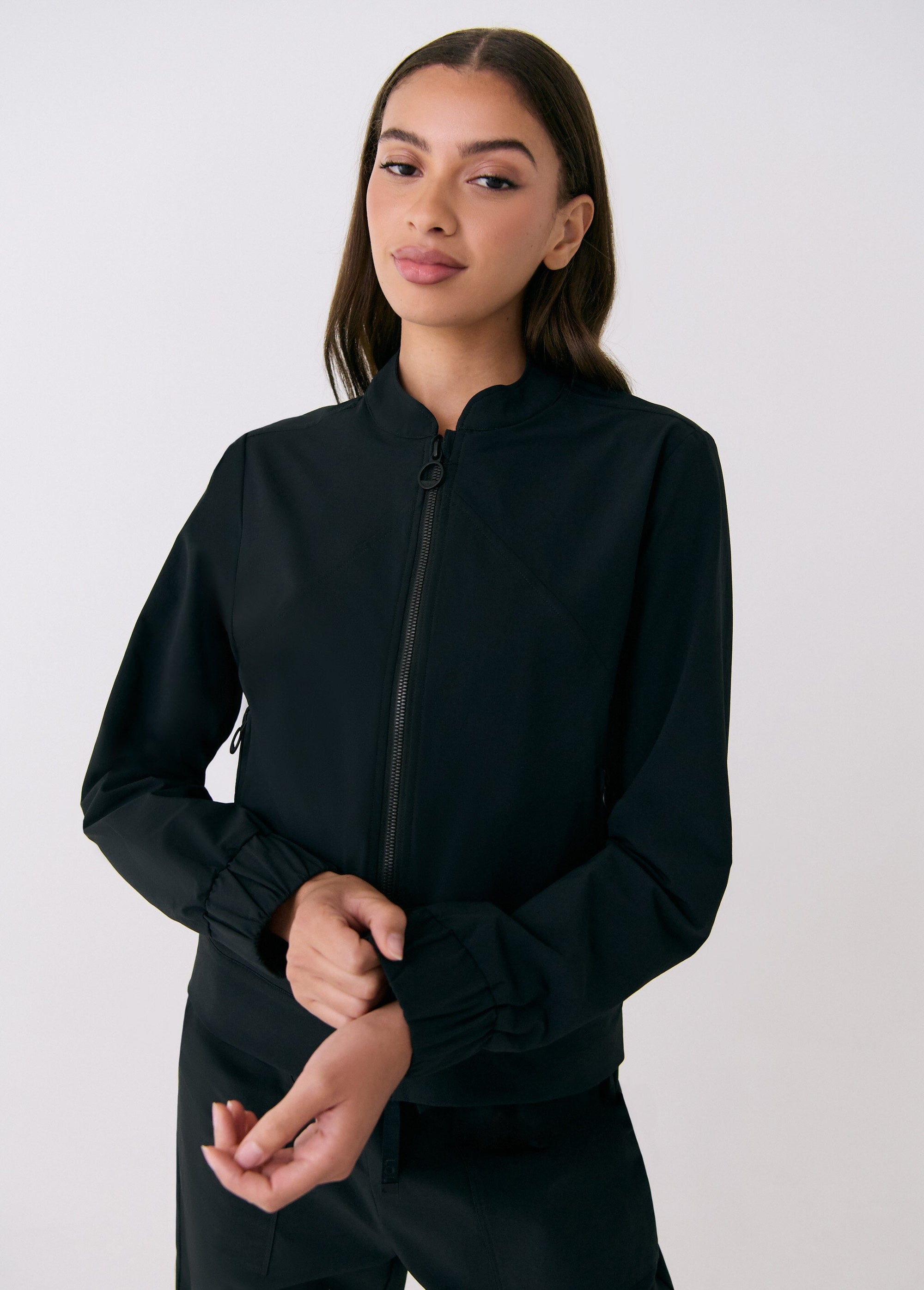 Black zip-up travel jacket with ribbed cuffs and mock neck collar, front on-model view