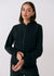Black zip-up travel jacket with ribbed cuffs and mock neck collar, front on-model view