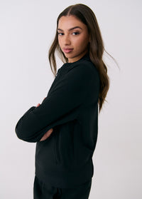 Black women's travel jacket with hood, shown from back angle on model with arms crossed