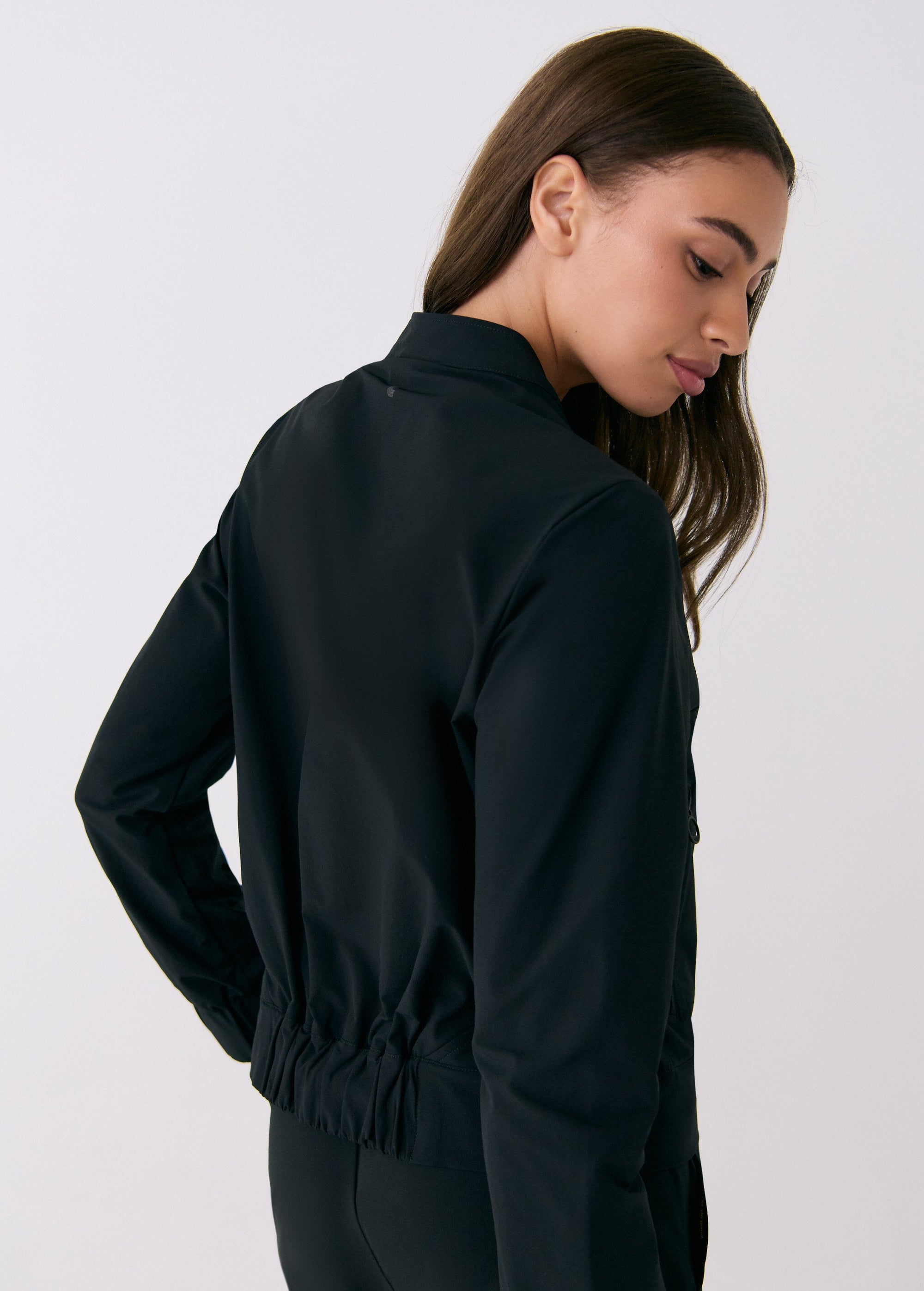 Black women's travel jacket back view showing elastic hem, long sleeves, and stand collar