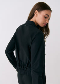 Black women's travel jacket back view showing elastic hem, long sleeves, and stand collar
