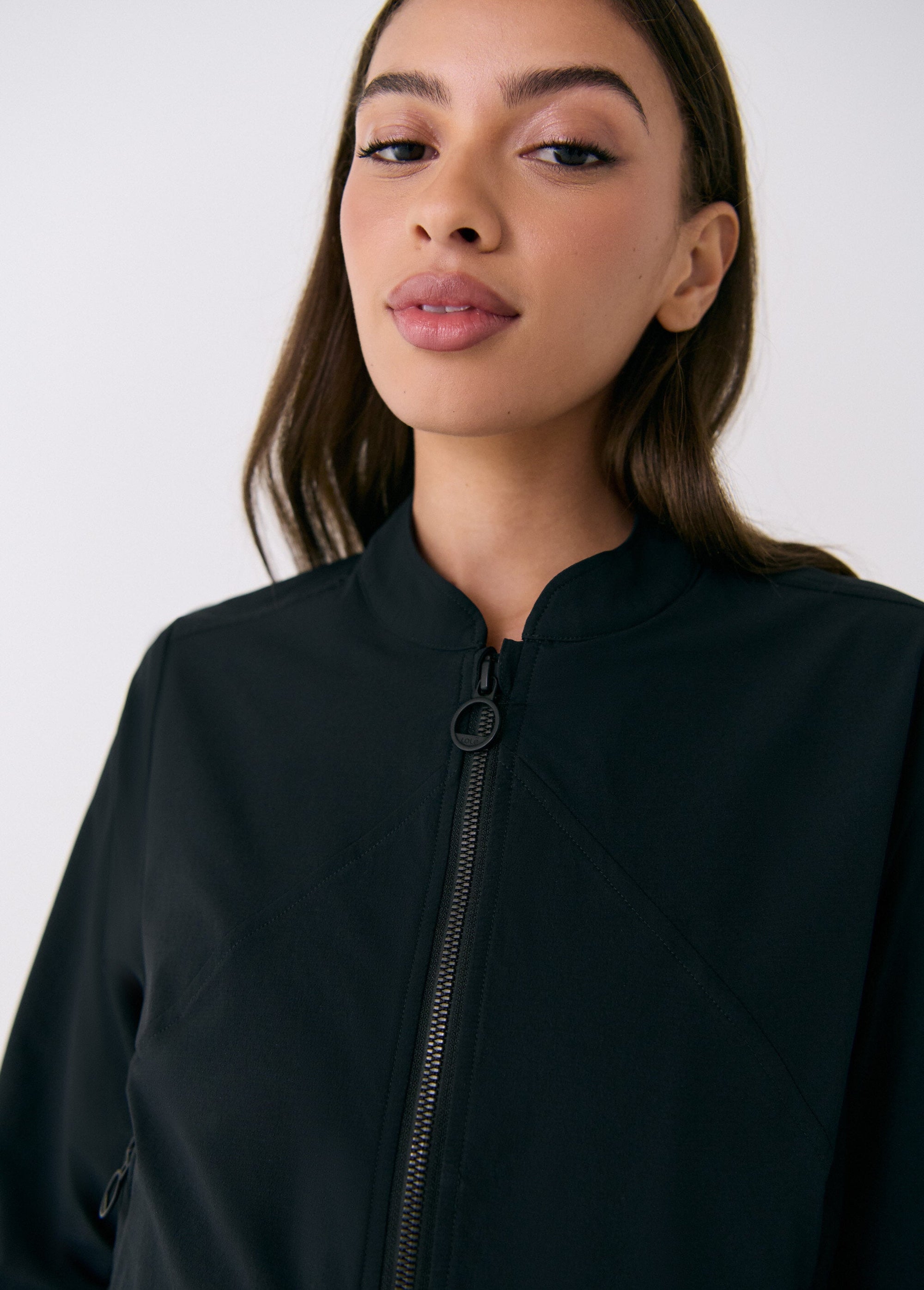 Black zip-up travel jacket with stand collar, close-up detail view on model