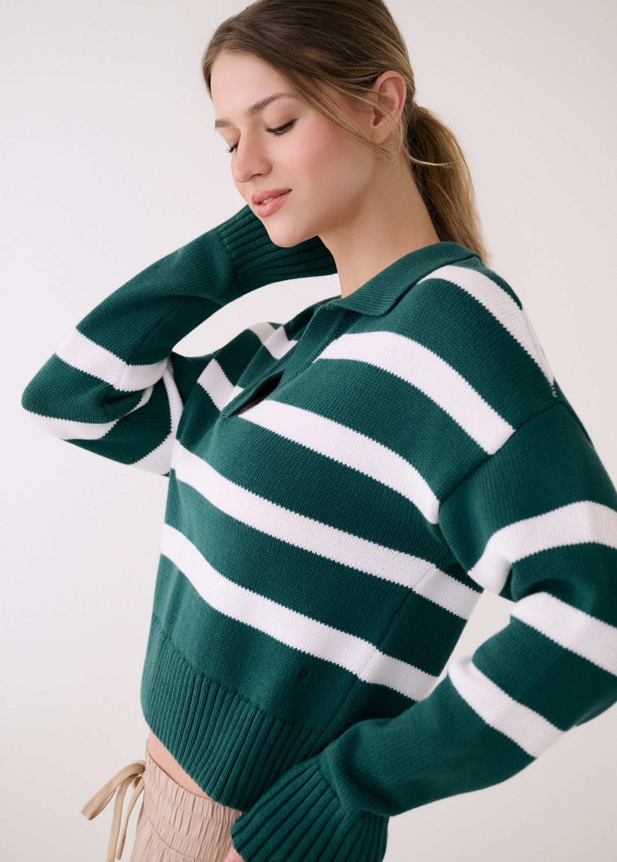 Green and white striped polo sweater with collar and long sleeves, worn by model