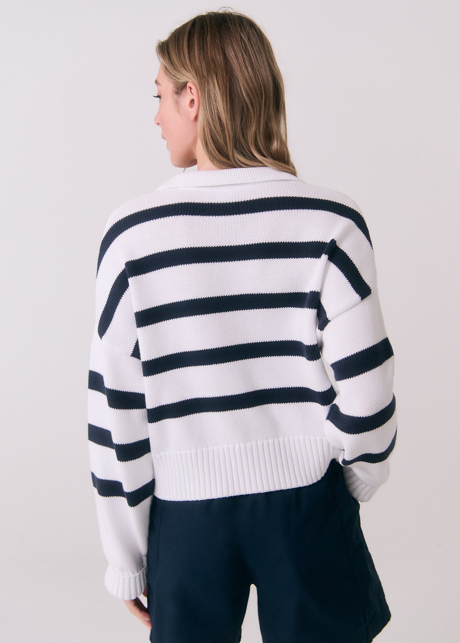White striped polo sweater with navy horizontal stripes, back view on model