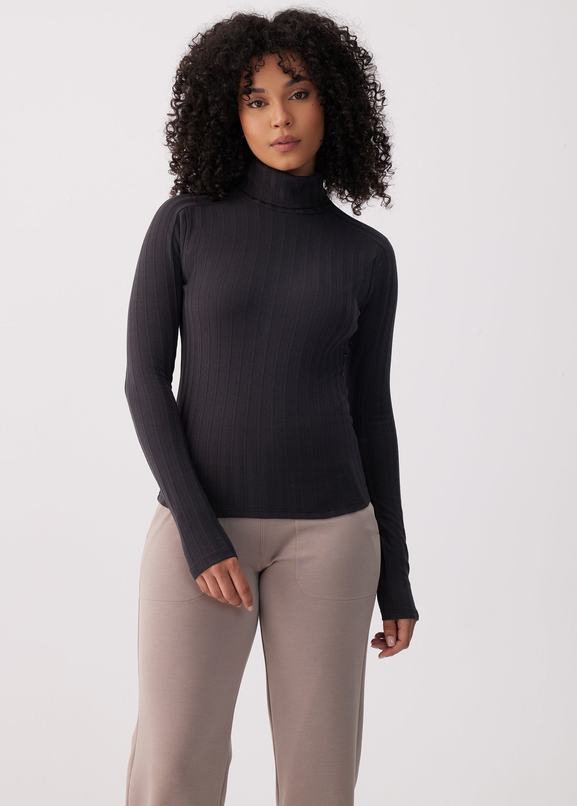 Women's ribbed turtleneck long-sleeve top in black, fitted silhouette, front view on model