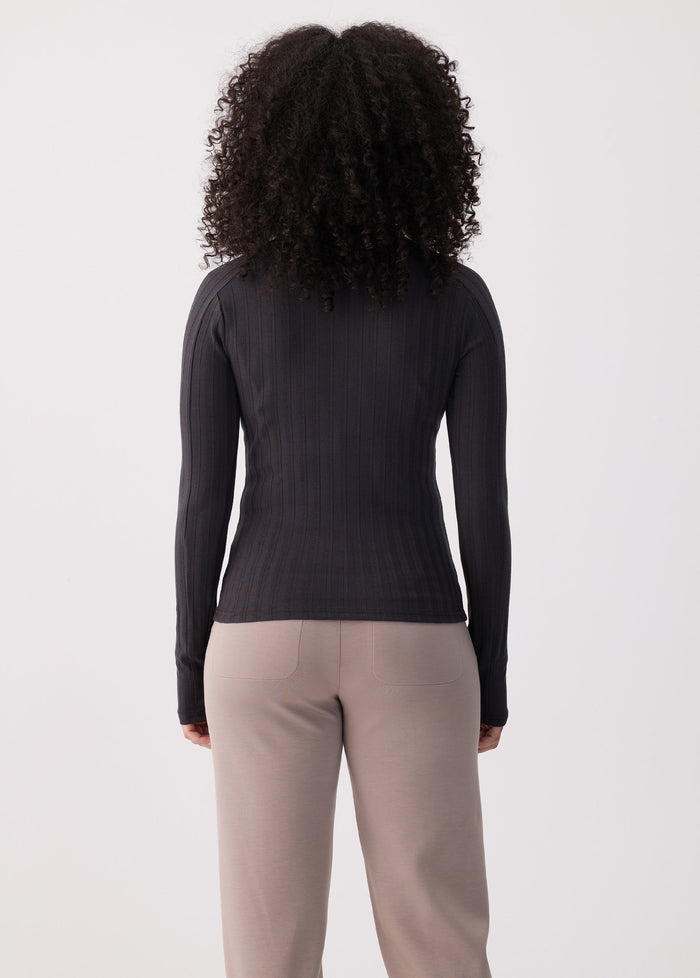 Women's black ribbed long-sleeve turtleneck top, back view on model with curly hair