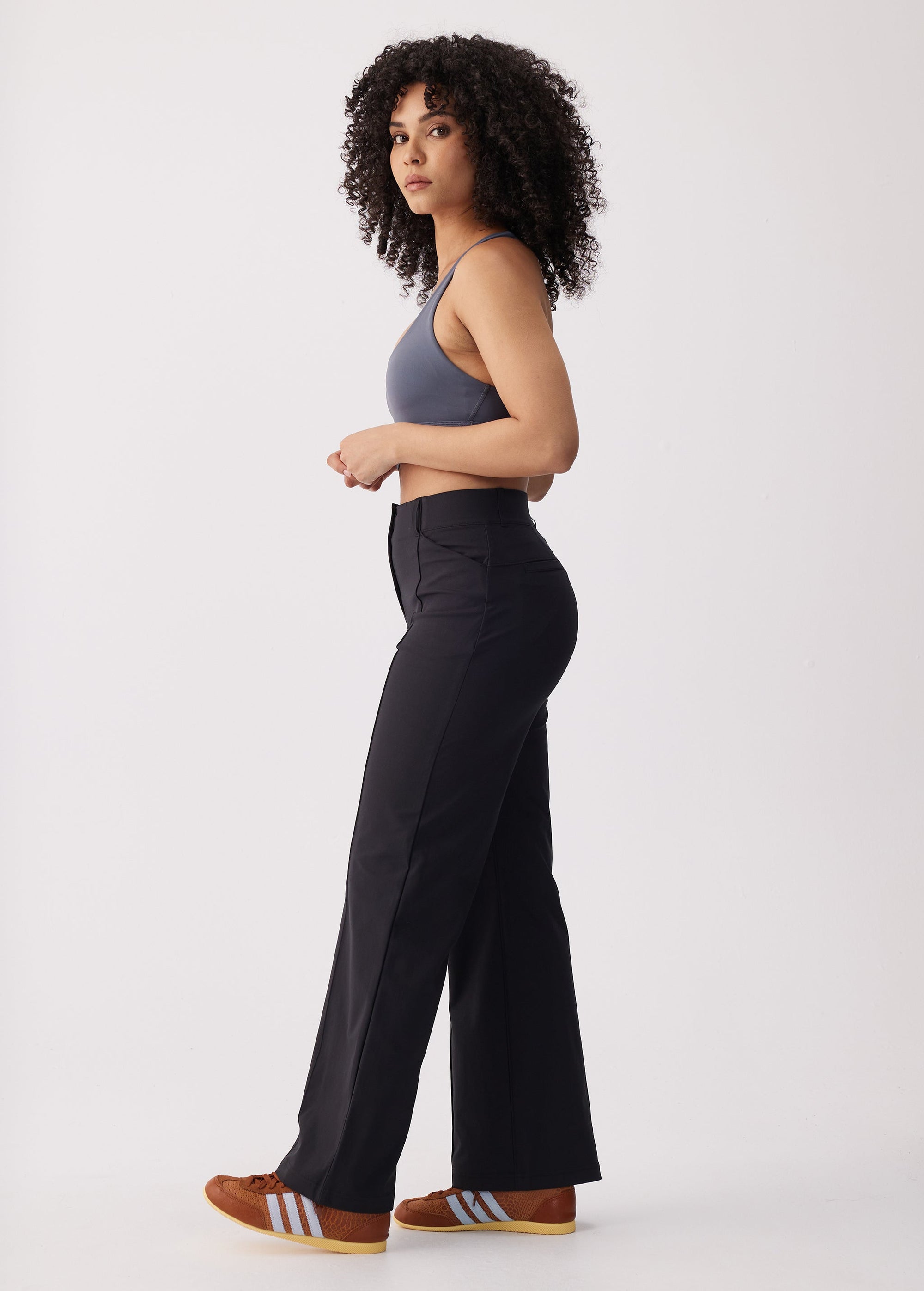 High-waisted black wide-leg travel trousers, side view on model with crop top