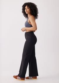 High-waisted black wide-leg travel trousers, side view on model with crop top