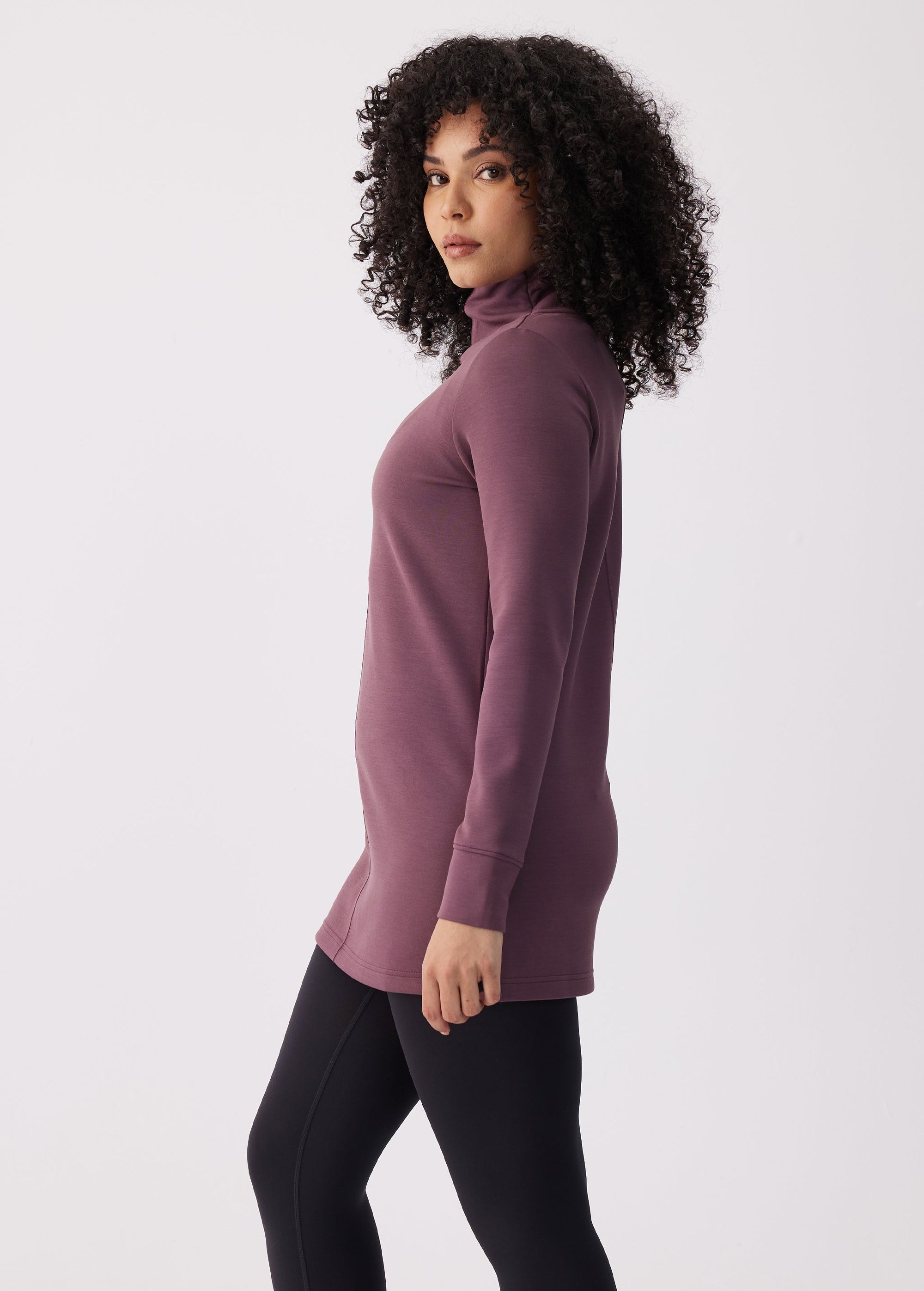 Women's long-sleeve turtleneck tunic top in mauve purple, side view, paired with black leggings