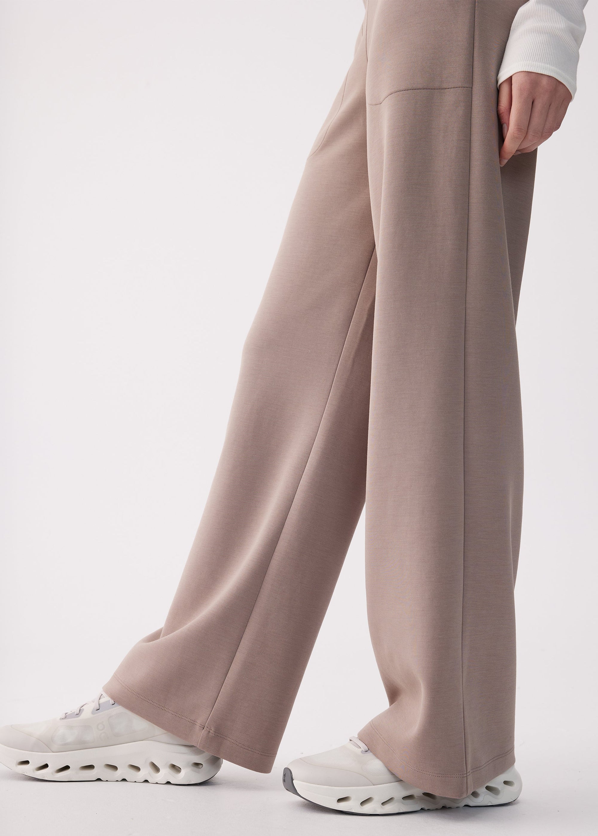Wide-leg pants in taupe, side view showing relaxed silhouette and white sneakers