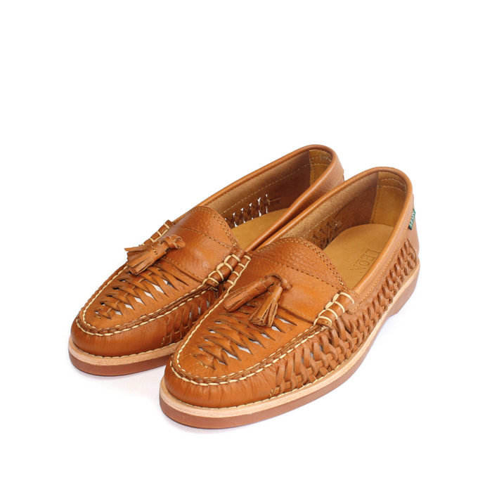 Brown leather woven loafers with tassels and white contrast stitching on white background