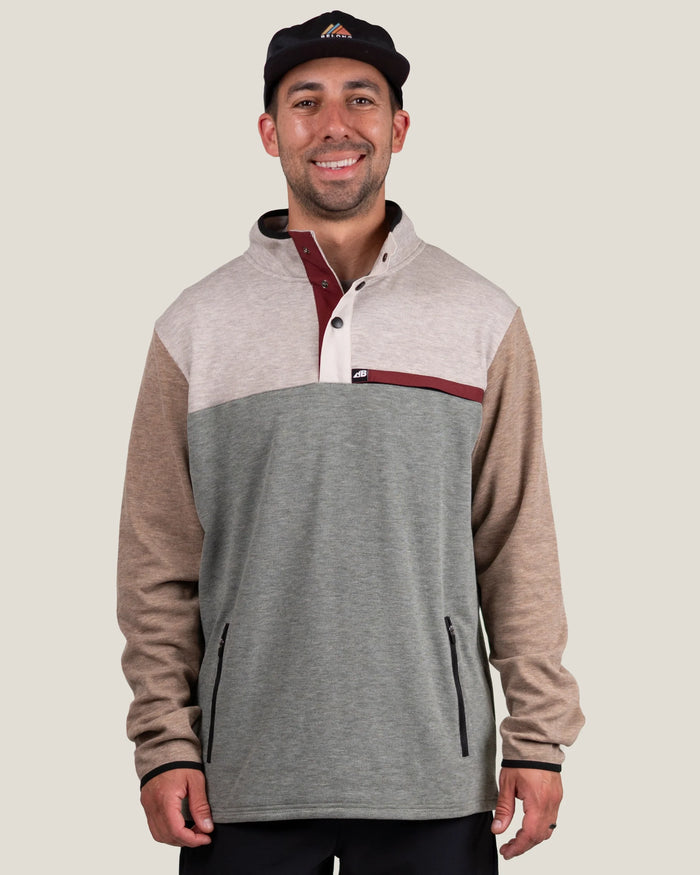 Men's color-block fleece pullover with snap collar, chest logo patch, and zip pockets, front view