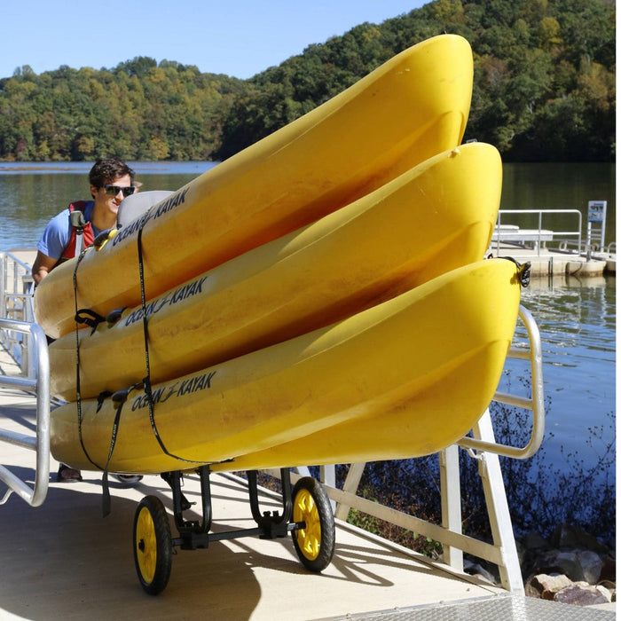 White wheeled kayak cart holding multiple yellow kayaks on dock by water