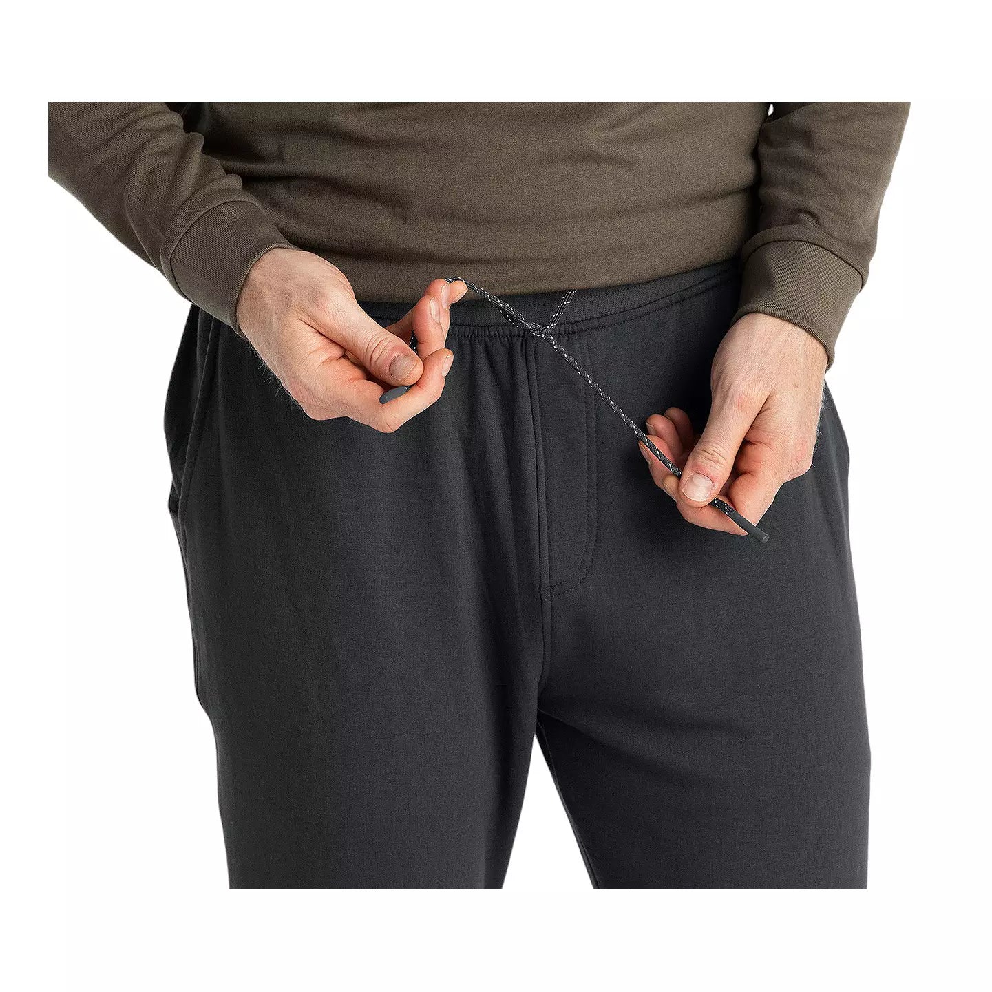 Close-up detail of men's jogger waistband with drawstring being adjusted by both hands